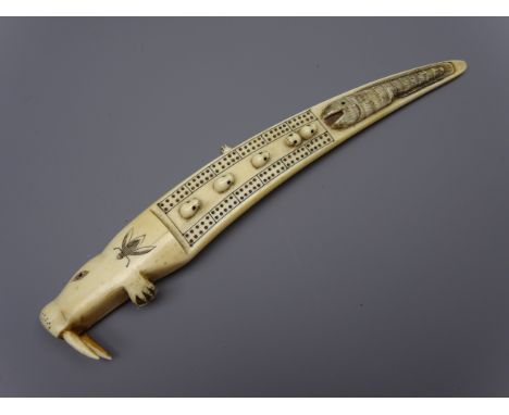 Scrimshaw Walrus tusk Cribbage board, decorated with seals heads and whale in relief, reverse with walrus and hunters in boat