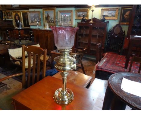 A Victorian brass oil lamp, having cranberry and clear glass shade with acid etched decoration on a circular foot (66cm).