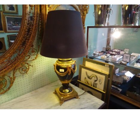 A decorative Regency-style table lamp, having extensive gilt decoration on a black ground, on a square base with four stylize