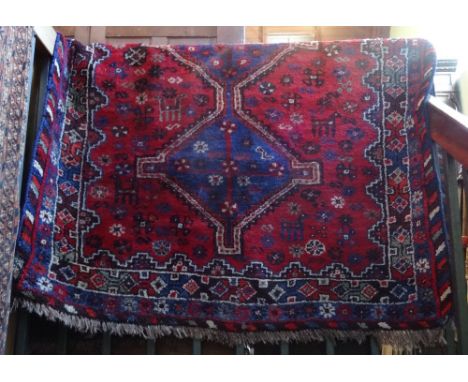 An Iranian hand made carpet in red and blue (180cm x 130cm).