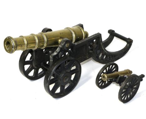 A Cast Brass Model of a Cannon, with ball cascabel, circular section trunnions and ringed barrel, on a black-painted, cast ir