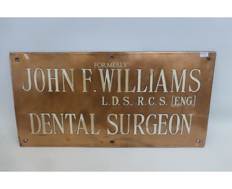 A John F. Williams Dental Surgeon rectangular copper wall plaque with cream enamel lettering, 18 x 9".