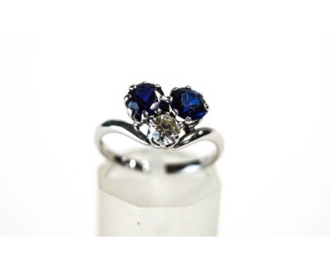 A three stone sapphire and diamond ring, the white mount stamped '18ct', the stones in a trefoil arrangement, the brilliant c