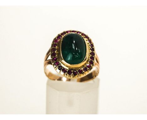 An Emerald and Ruby cluster ring, the oval cabochon enclosed by twenty six small rubies, finger size J1/2, 6g gross