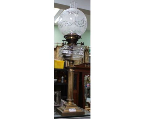 A BRASS COLUMN BASE GLASS RESERVOIR OIL LAMP with etched globular shade 