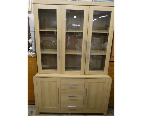 A modern light oak dresser fitted three glazed doors above drawers and cupboards under 