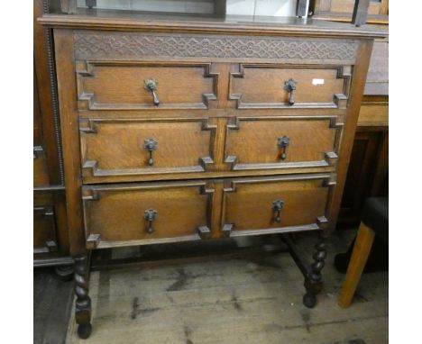 An antique style oak chest of drawers with fielded panel fronts and barley twist legs 
