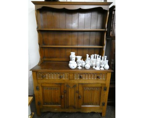 A medium oak reproduction dresser with closed panel back, two drawers and cupboards under, with linen fold panel carvings 