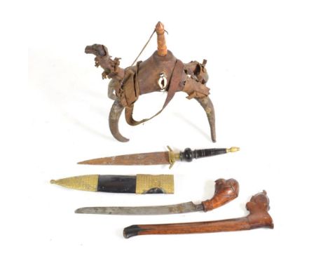 An Indonesian Bade Bade, with slender curved blade, the wood hilt carved as the head of a parrot, with wood scabbard; a Tuare