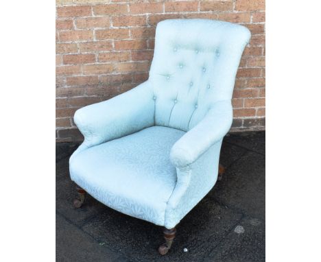 A VICTORIAN BUTTON UPHOLSTERED ARMCHAIR  on turned supports with brass and ceramic casters