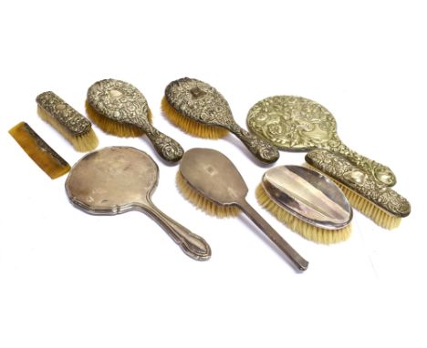 A GROUP OF SILVER MOUNTED DRESSING TABLE ITEMS  comprising; two embossed oval hair brushes and another shaped oval and engine