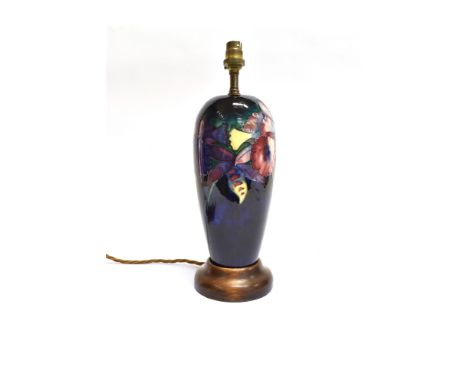 A MOORCROFT POTTERY TABLE LAMP DECORATED IN THE 'ORCHID' PATTERN  on a blue ground, 38cm high including wooden base and elect