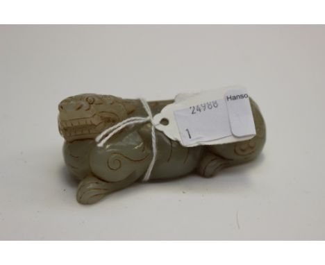 A Chinese archaistic jade carving of a crouching mythical lion with archaic 'C' scrolls on its hinds quarters, its head turn 