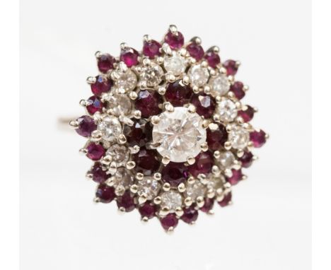 An 18ct white gold ruby and diamond cluster ring, claw set central diamond of approx 0.75ct, with three outer borders set alt