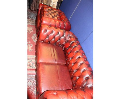 A traditional red leather deep buttoned three piece suite, comprising two seater settee, an armchair and a pouffe (3) 