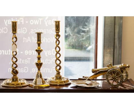 A pair of gilded brass spiral twist candle sticks, on circular folded bases, together with a gilt brass cannon on stand, anot