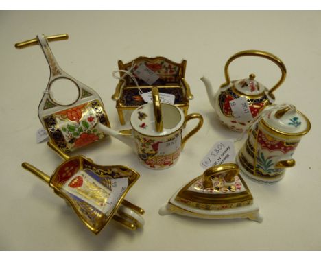 A collection of seven assorted Royal Crown Derby miniatures, including wheelbarrow, iron, kettle, bench, garden roller, and m