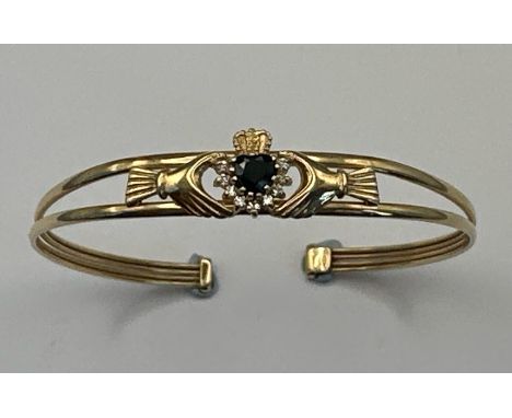 A hallmarked 9ct gold Claddagh style bangle set with sapphire and cubic zirconia. Gross weight 5.47g. / SF 
