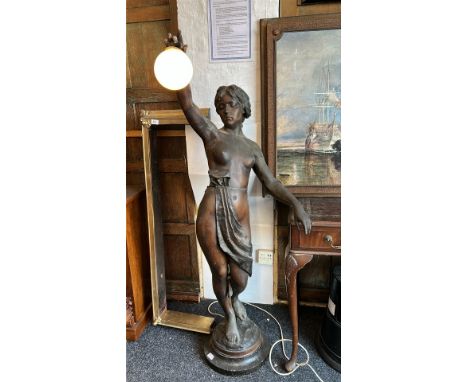 A bronzed spelter Art Deco floor lamp in the form of a nude female on marble base with bulb suspended from her right hand, in