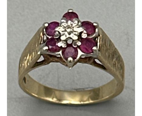 A ruby and illusion set diamond flower cluster ring with bark effect shoulders in hallmarked 9ct gold, 1977. Average diameter