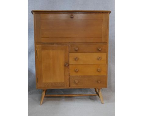A mid century vintage light elm Ercol drinks cabinet with fall front above a cupboard and drawers raised on splay stretchered