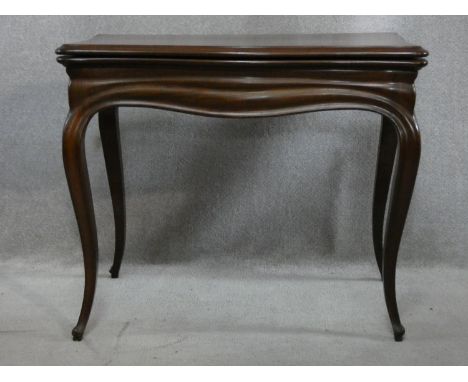 An antique mahogany Louis XV style fold over top card table with tooled leather inset top and pull slide action raised on sle