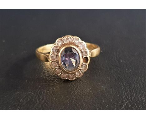 BLUE TOPAZ AND CLEAR GEM SET CLUSTER RINGthe central oval cut blue topaz approximately 1ct in bezel setting and clear gem set