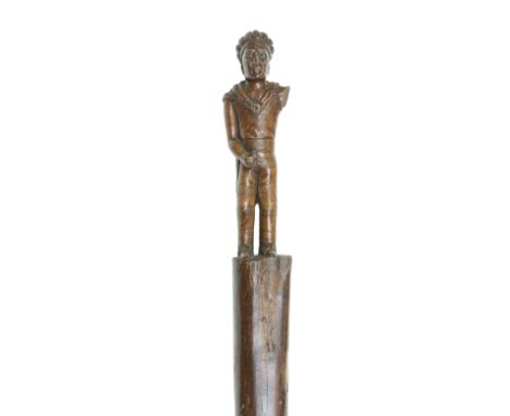 A NATIVE AMERICAN CARVED WOODEN STAFFOf tapered form, the finial carved as a standing chieftain wearing headdress (lacking ar