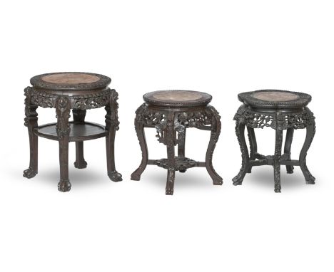 THREE CHINESE CARVED HARDWOOD STANDSEach with a circular top inset with rouge marble, with scroll legs terminating in scroll 