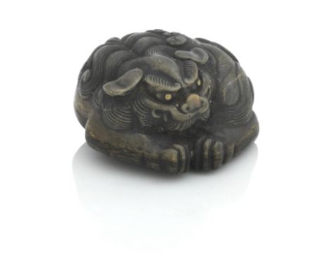 A JAPANESE HORN NETSUKECarved as a curled up lion dog, with brass eyes, unsigned.4cm diameter.For further information on this