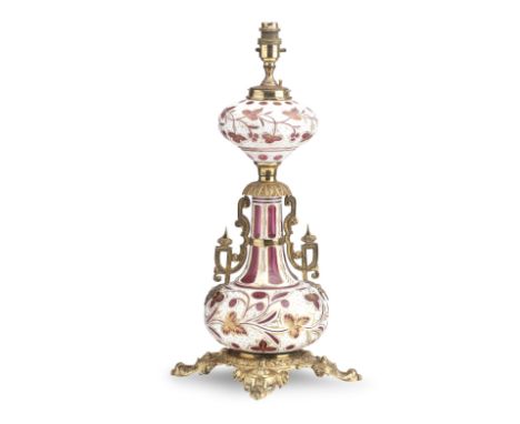 A BOHEMIAN ORMOLU CASED RUBY GLASS TABLE LAMP19th centuryFormerly a paraffin lamp, the baluster glass body in white and cut a