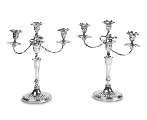 A PAIR OF GEORGE III STYLE SILVER PLATE THREE LIGHT CANDELABRAOval fluted bases and columns with scrolling branches, height 3