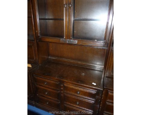 An Ercol glass topped dark-wood dresser with six drawers.