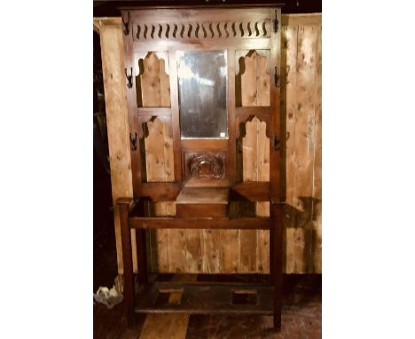An early 20th Century oak hall stand, moulded cornice on open carved panel, fitted with rectangular mirror, mounted with iron