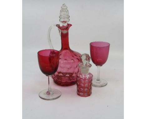 A cranberry glass decanter, two glasses, and a scent bottle. (4)