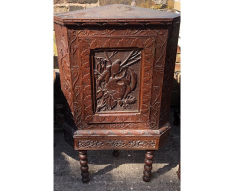 An early 20th century oak corner cabinet, foliate carved front on a stippled ground, a carved cornice obove a carved single d