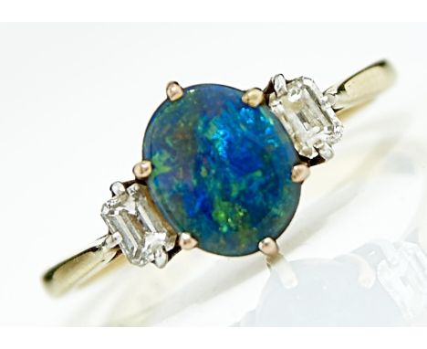 A BLACK OPAL AND DIAMOND RING. THE BLACK OPAL OF APPROX 7 X 9MM FLANKED BY BAGUETTE DAIMONDS IN 18CT GOLD, UK MARKS OBSCURED,