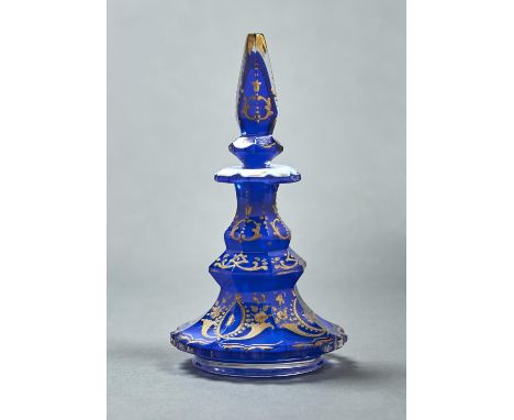 A CASED GLASS SCENT BOTTLE AND STOPPER, C1860, OF OPAL CASED IN BLUE GLASS WITH RAISED GILDING, 16.5CM H One or two tiny nick
