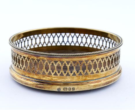 AN ELIZABETH II SILVER GILT WINE COASTER, PIERCED BENEATH REEDED RIM, INSET TURNED MAHOGANY BASE, 13CM DIA, BY C J VANDER LIM