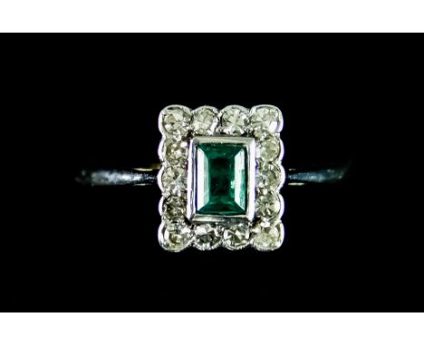 An Emerald and Diamond Ring, set with a centre faceted emerald stone approximately .50ct, surrounded by small brilliant cut d