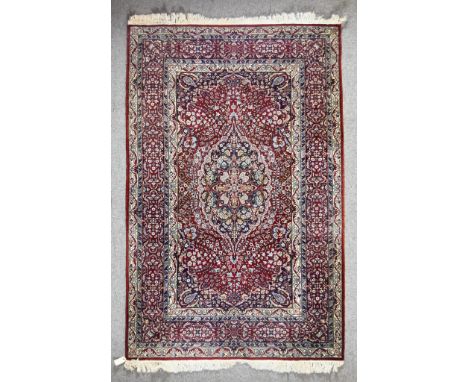 An Early 20th Century Tabriz Rug, woven in colours of ivory, navy blue and wine, with a bold central stylised floral medallio