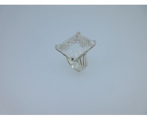 A modern rock crystal statement ring, the large fantasy cut rectangular rock crystal 2½ cm x 2cm in a four claw collet with d