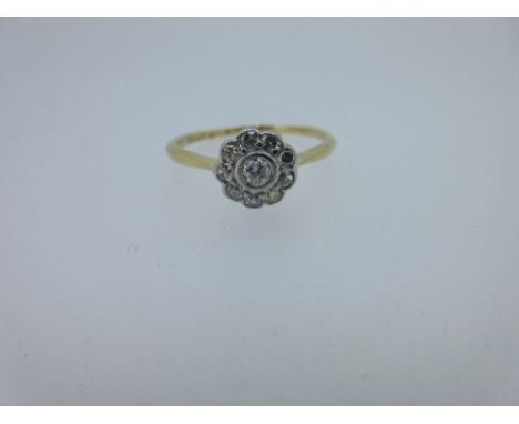 A diamond flowerhead cluster ring, the round brilliant cut diamond, millegrain collet set in the centre of nine single cut di