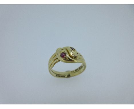 A Victorian double snake ring set with a diamond and a ruby, the entwined serpents, their heads each with a round facetted st