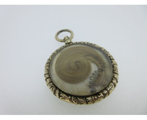 A William IV memorial pendant with curled hairwork, the circular pendant with a cast foliate frame and swivelling suspensory 