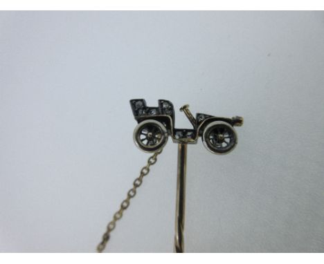 A diamond set vintage car stick pin, the open-topped car, with freely turning wheels, highlighted by rose cut diamonds, with 