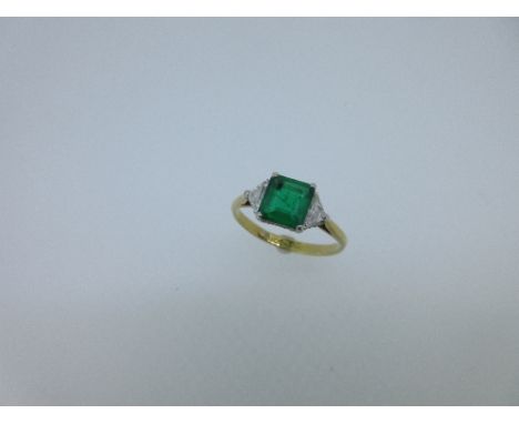 An emerald and diamond 3 stone ring, the square emerald cut emerald between two kite shaped diamonds, all collet set, the sto