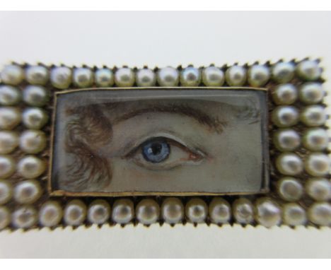 A pearl set lover's eye brooch, the rectangular painting depicting a blue eye under a delicately arched brow and a lock of cu