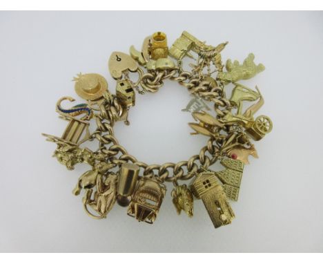 A 9ct gold charm bracelet with a large quantity of charms, the curb link bracelet with padlock catch and safety chain, Birmin