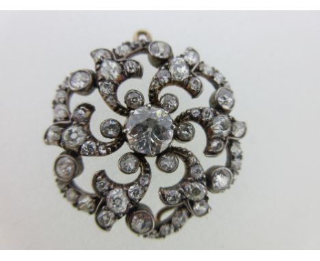 A late 19th century circular diamond brooch / pendant, of pierced design and set to the centre with an old round cut diamond,